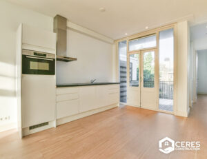 Modern kitchen with white cabinets, built-in oven, and access to a balcony