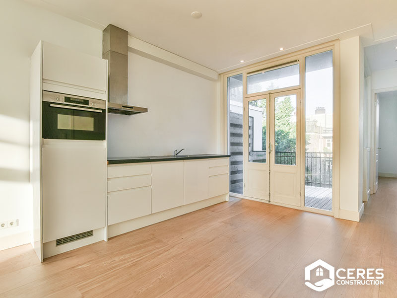 Modern kitchen with white cabinets, built-in oven, and access to a balcony