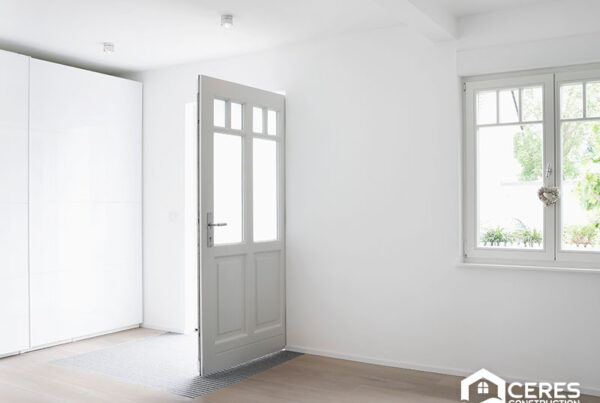Bright entryway with a white door, hardwood flooring, and a window