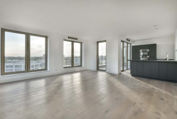 For this image, the alt text could be "Modern open-concept living space with hardwood flooring and large windows, adjacent to a kitchen