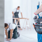 Construction workers with tool belt, measuring and cutting materials