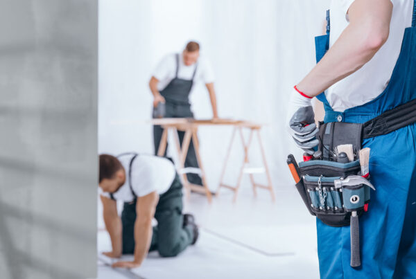 Construction workers with tool belt, measuring and cutting materials