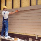 Construction worker installing siding on a house