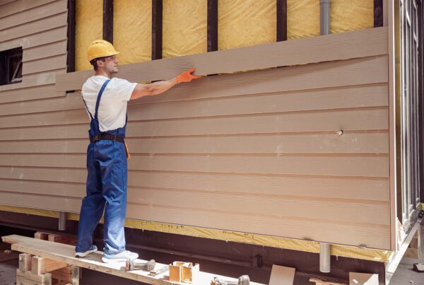 Construction worker installing siding on a house