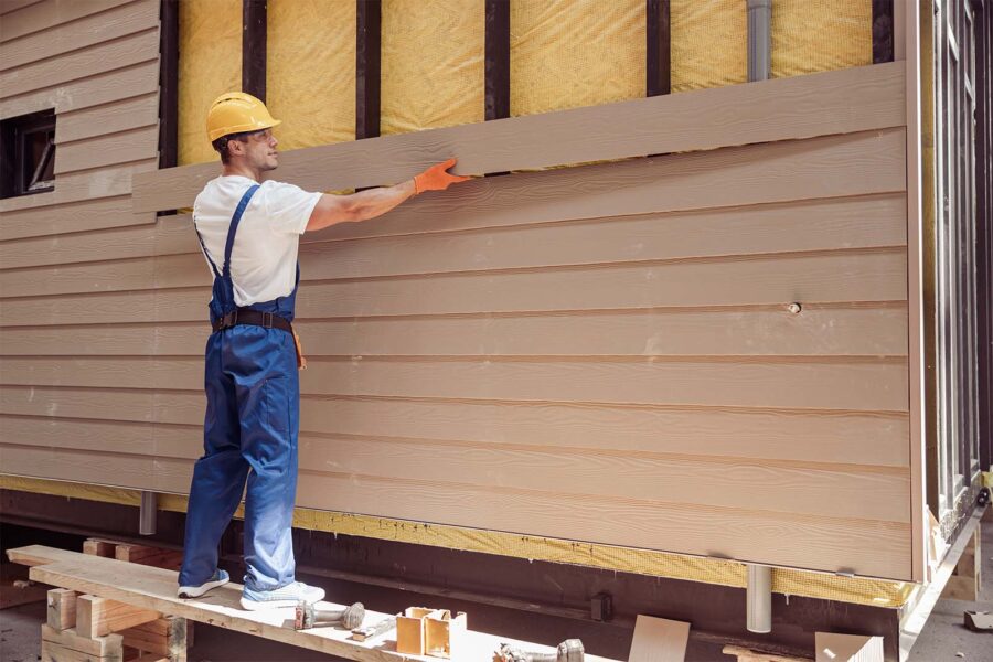 Construction worker installing siding on a house