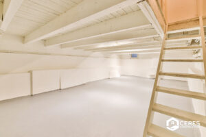 Clean and renovated basement with wooden beams and a ladder