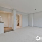 Spacious living area with new carpet and a view of the kitchen and stairs