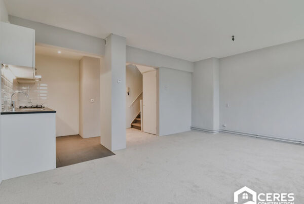 Spacious living area with new carpet and a view of the kitchen and stairs